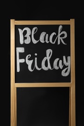 Photo of Board with phrase Black Friday on dark background