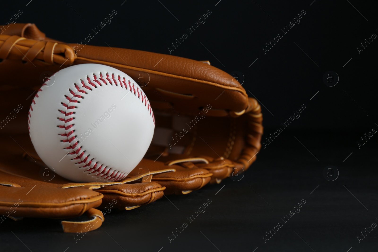 Photo of Catcher's mitt and baseball ball on black background, space for text. Sports game