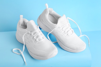 Photo of Stylish white sports shoes on light blue background