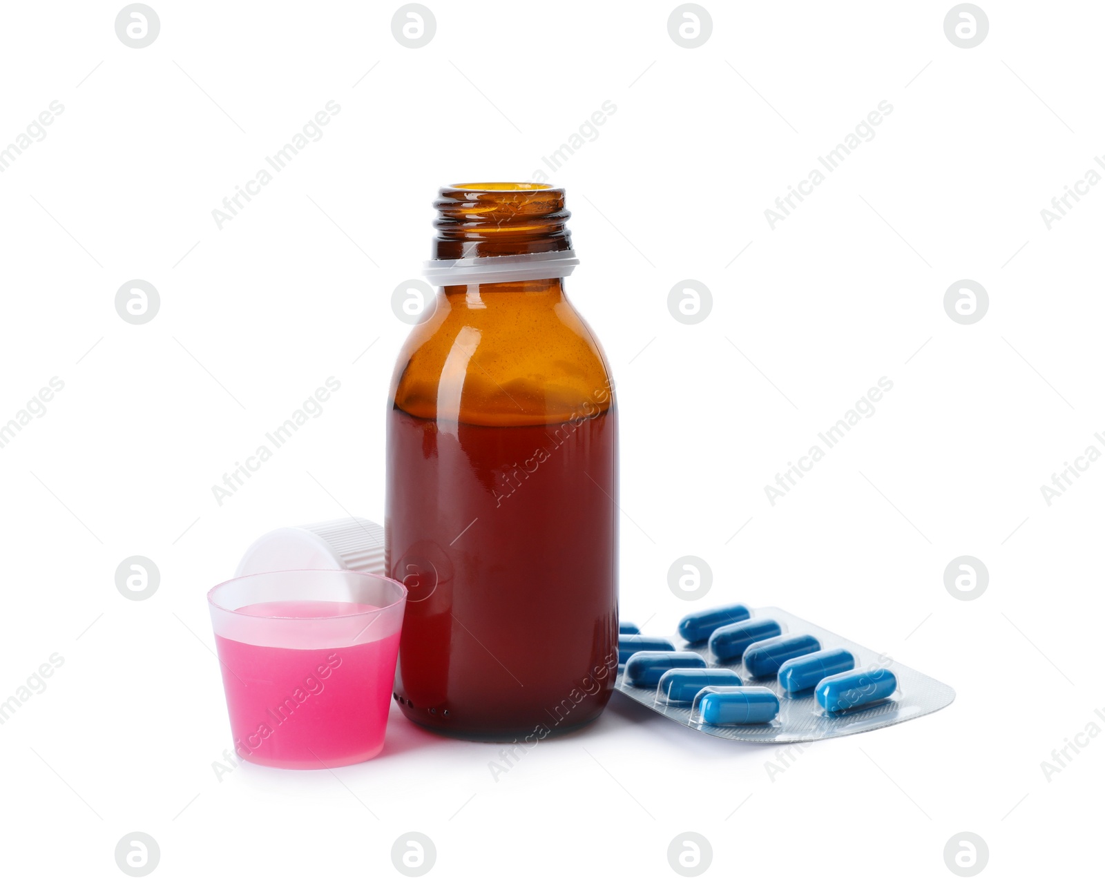 Photo of Measuring cup and bottle of cough syrup with pills on white background