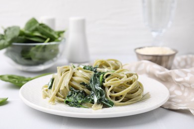 Tasty pasta with spinach and sauce on white table