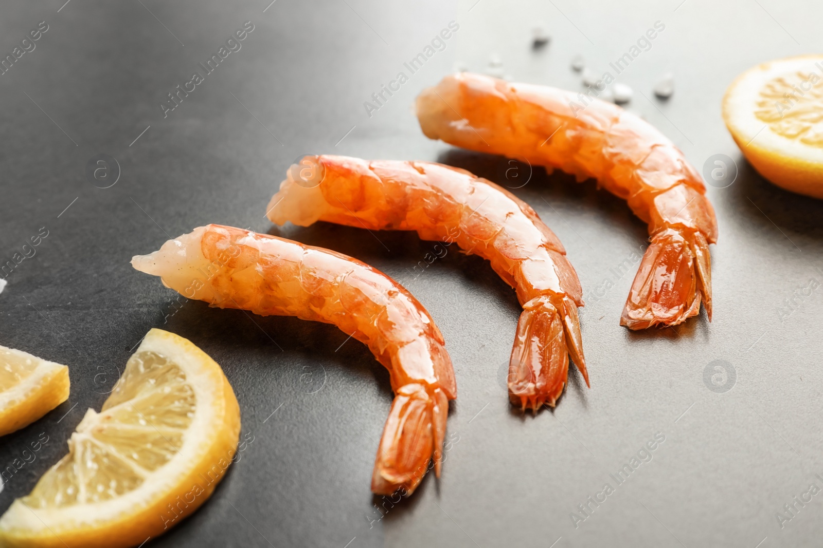 Photo of Delicious shrimps with lemon on gray background