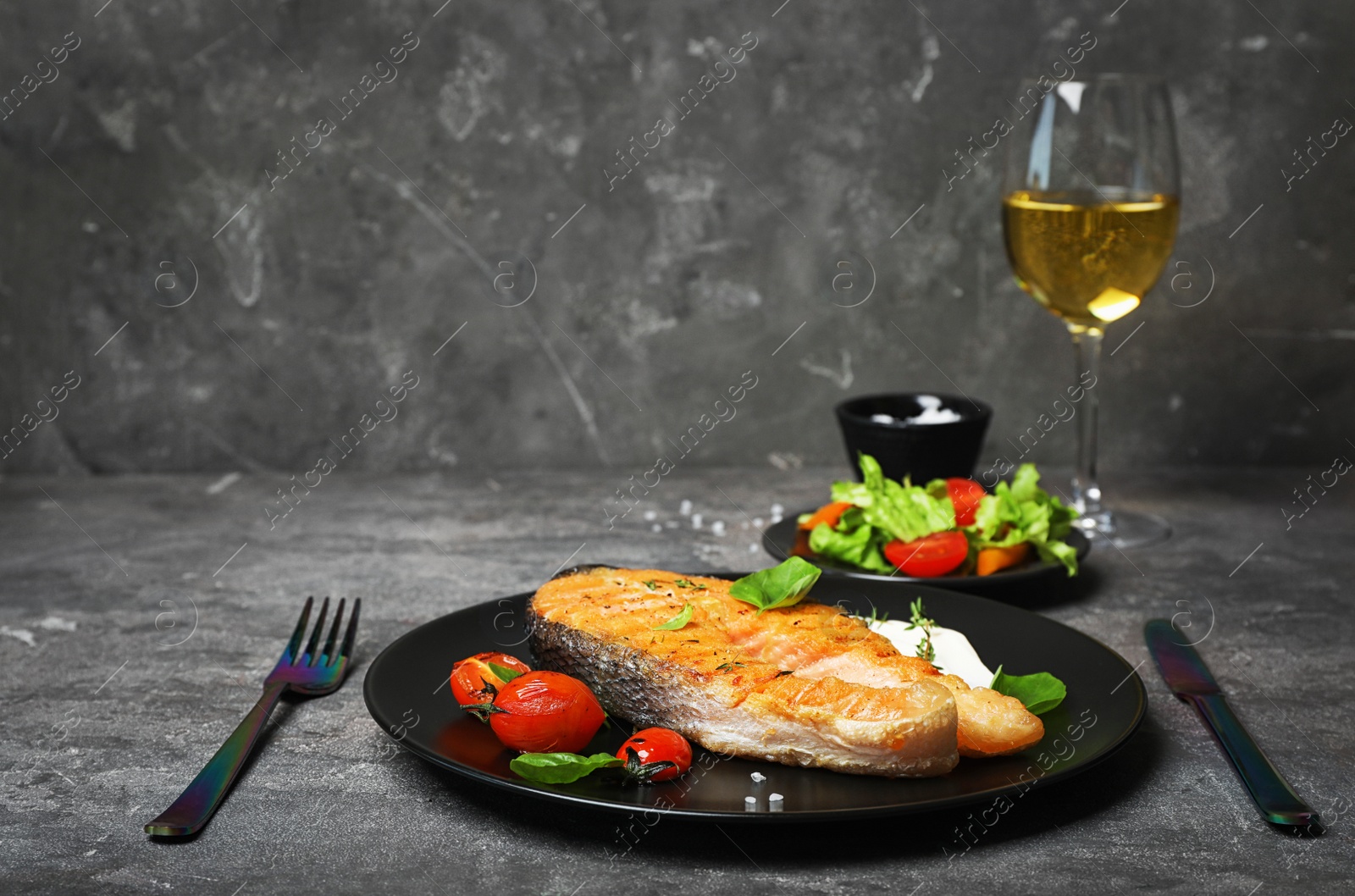 Photo of Tasty salmon steak served with glass of wine on table