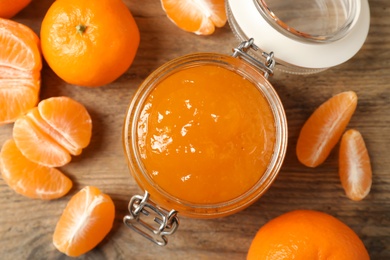 Photo of Flat lay composition with tasty tangerine jam on wooden table