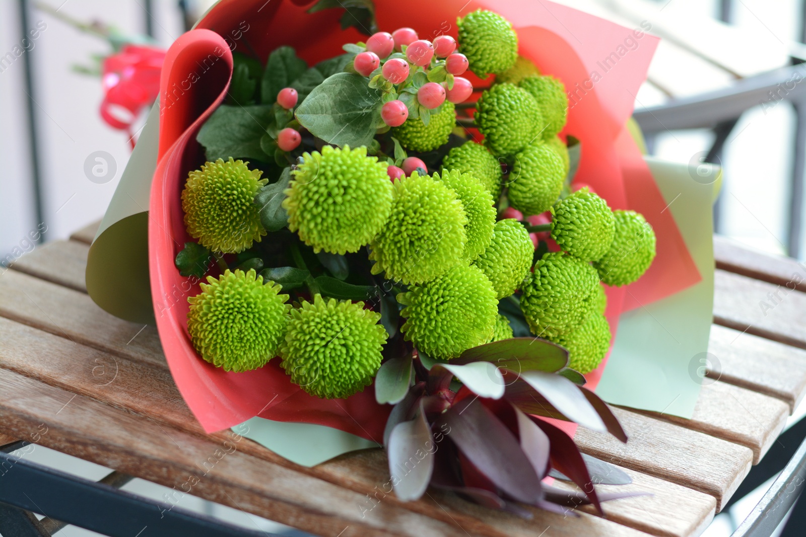 Photo of Bouquet of beautiful flowers wrapped in paper on wooden table, closeup