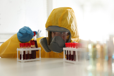 Photo of Scientist in chemical protective suit working with blood samples at laboratory. Virus research