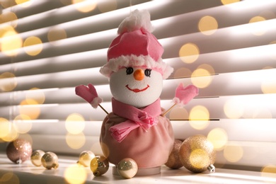 Decorative snowman and golden Christmas balls on window sill