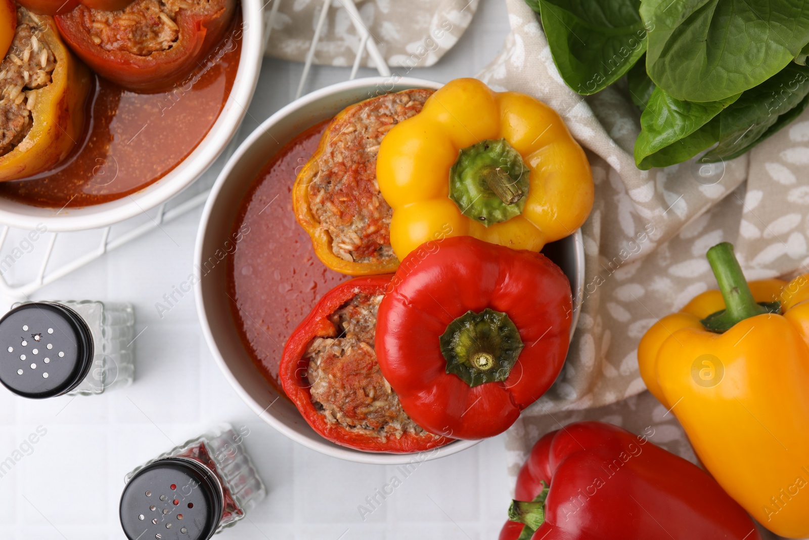 Photo of Delicious stuffed bell peppers on white tiled table, flat lay