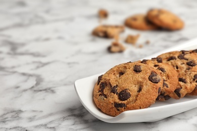 Photo of Plate with chocolate chip cookies on marble background, space for text