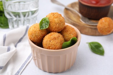 Photo of Bowl of delicious fried tofu balls with basil on white table