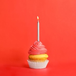 Birthday cupcake with candle on red background