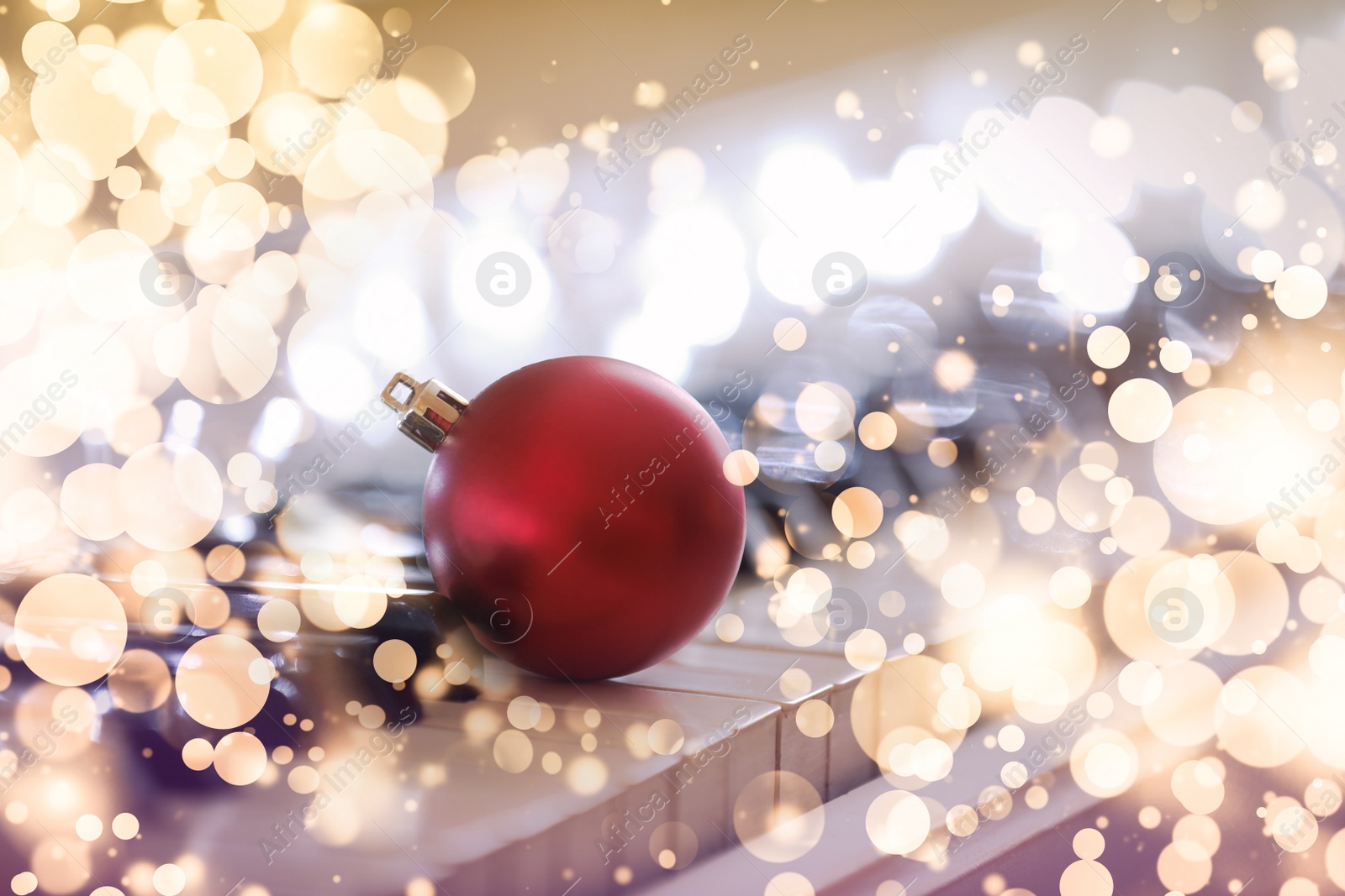 Image of Beautiful red bauble and fairy lights on piano, closeup. Christmas music. Bokeh effect