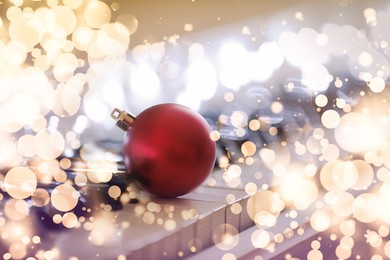 Beautiful red bauble and fairy lights on piano, closeup. Christmas music. Bokeh effect