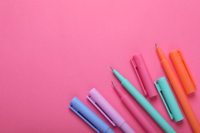 Many colorful markers on pink background, flat lay. Space for text