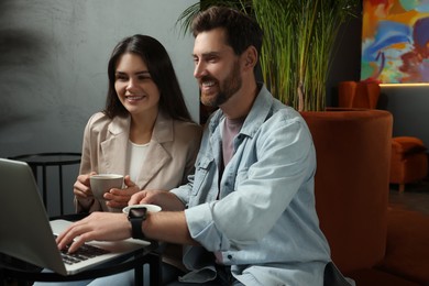 Photo of Couple with coffee and laptop spending time together in cafe