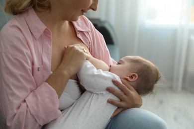 Young woman breastfeeding her baby at home, closeup