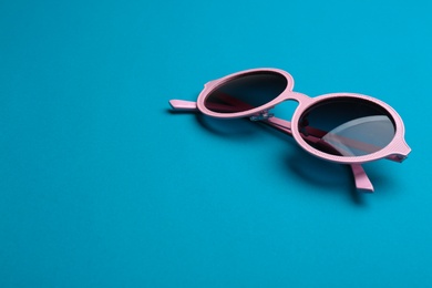 Photo of Stylish sunglasses on blue background, space for text. Fashionable accessory