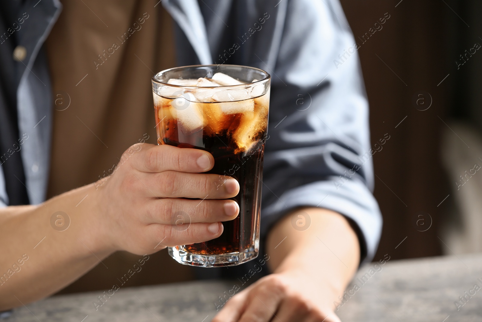 Photo of Man with glass of cold cola at table indoors, closeup
