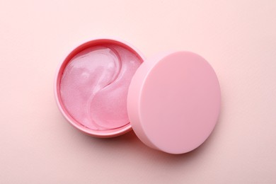 Under eye patches in jar with lid on light pink background, top view. Cosmetic product