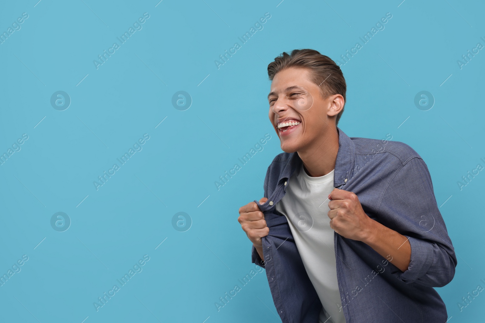 Photo of Emotional sports fan celebrating on light blue background. Space for text