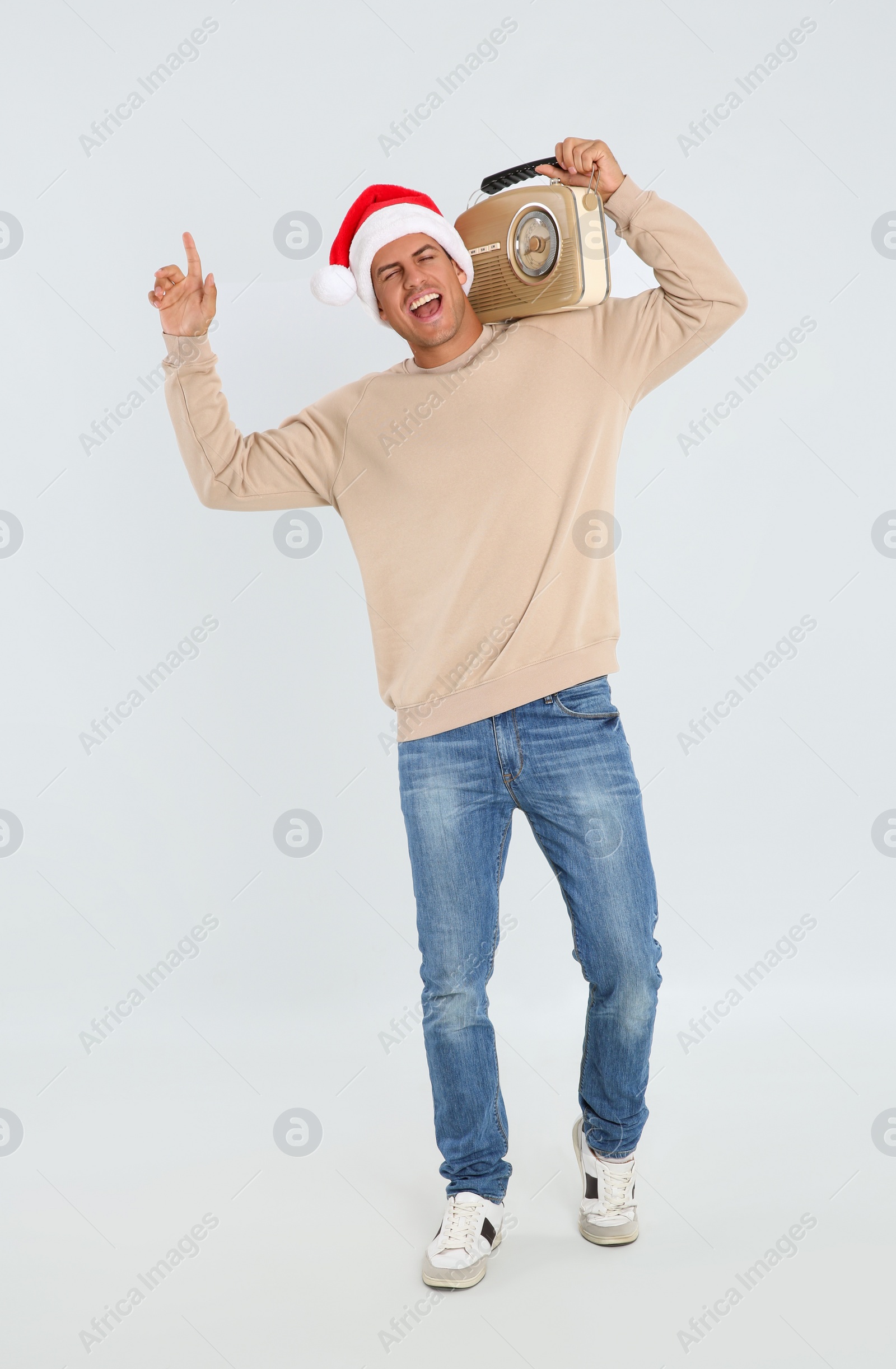 Photo of Emotional man with vintage radio on white background. Christmas music