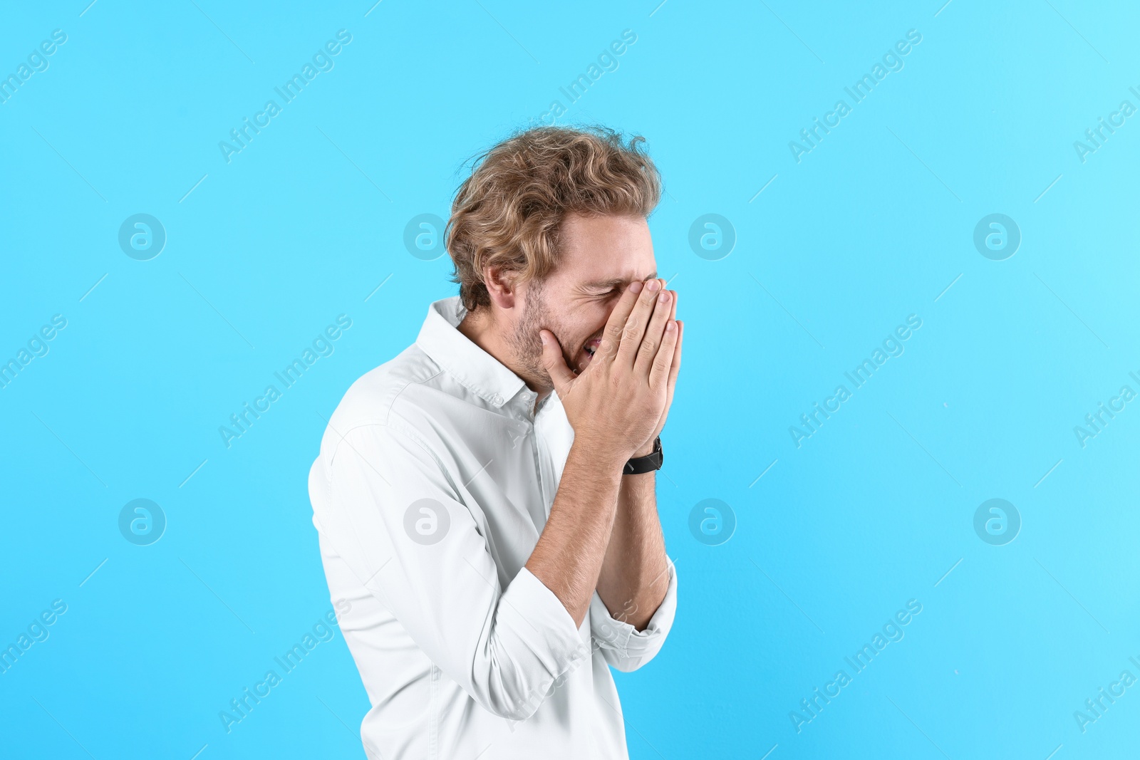 Photo of Handsome young man laughing on color background