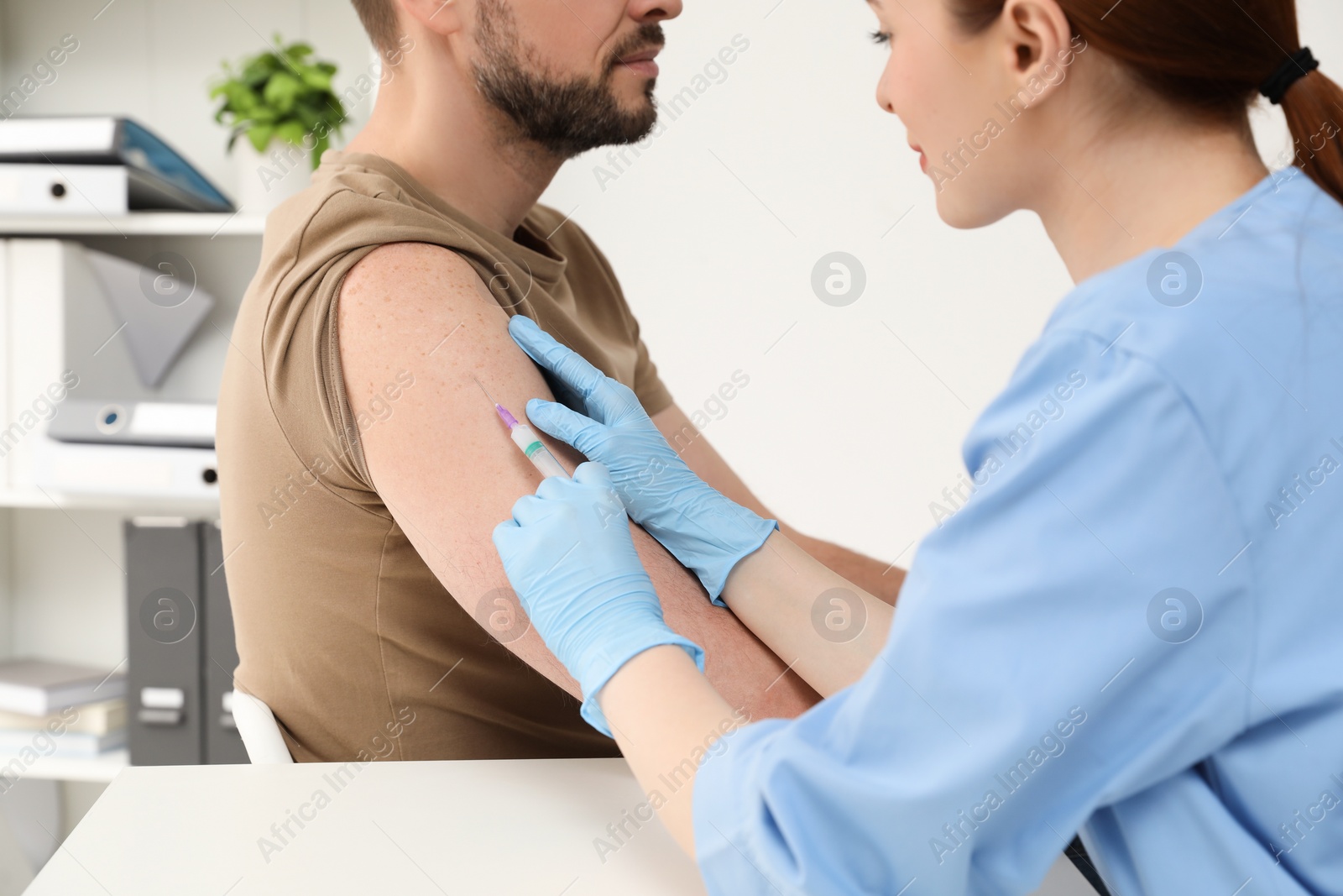 Photo of Doctor giving hepatitis vaccine to patient in clinic, closeup