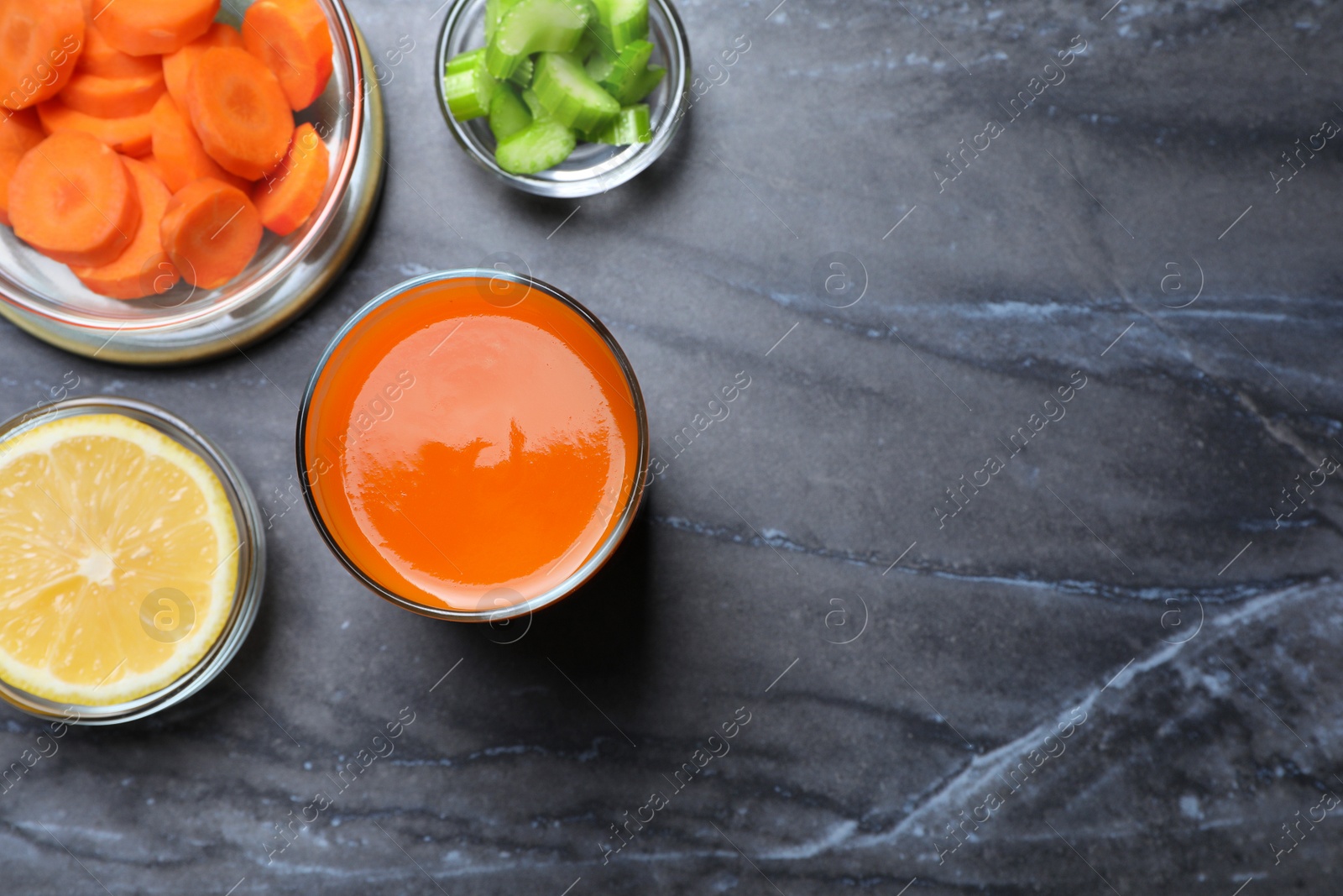 Photo of Tasty carrot juice and ingredients on black marble table, flat lay. Space for text