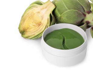 Package of under eye patches and artichokes on white background, closeup. Cosmetic product