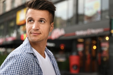 Photo of Portrait of handsome young man on city street. Space for text