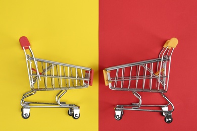 Flat lay composition with empty shopping trolleys on color background