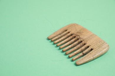 Photo of Wooden comb with lost hair on green background. Space for text
