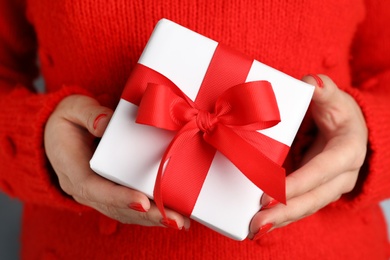 Photo of Young woman holding Christmas gift, closeup view