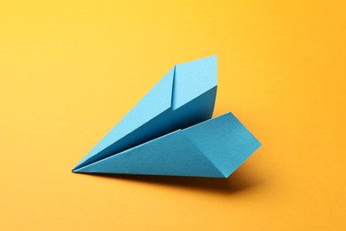 Photo of Handmade light blue paper plane on yellow background