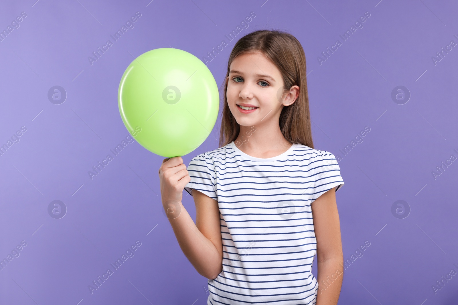 Photo of Happy girl with green balloon on violet background