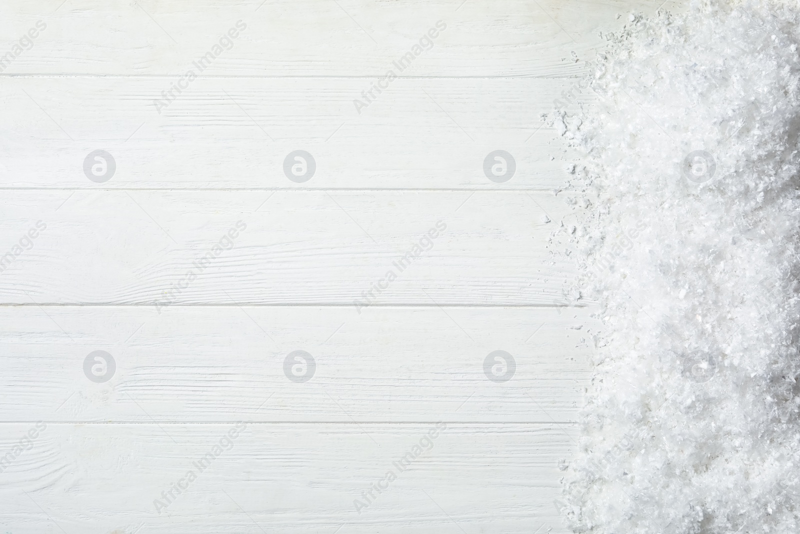 Photo of Snow and space for text on white wooden background, top view. Christmas season