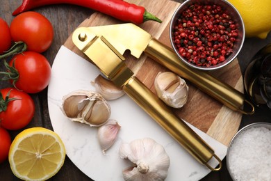 Photo of Different fresh ingredients for marinade and garlic press on wooden table, flat lay