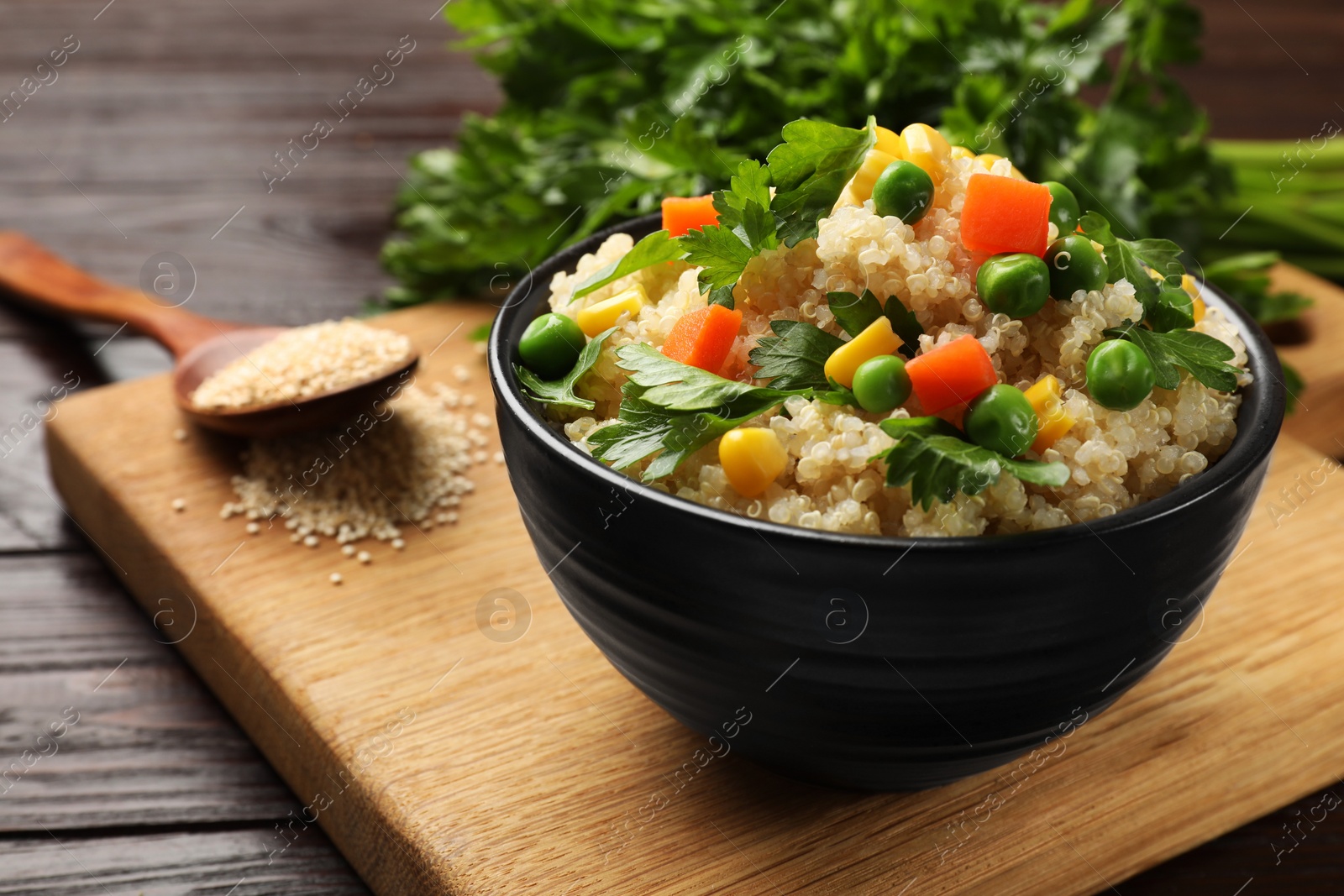 Photo of Tasty quinoa porridge with vegetables in bowl on wooden table, closeup