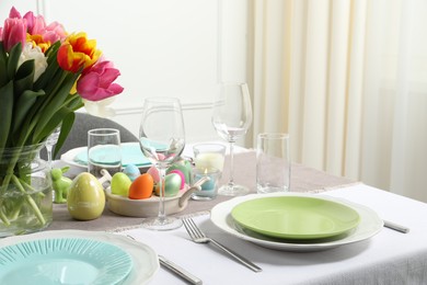 Photo of Easter celebration. Festive table setting with beautiful flowers and painted eggs