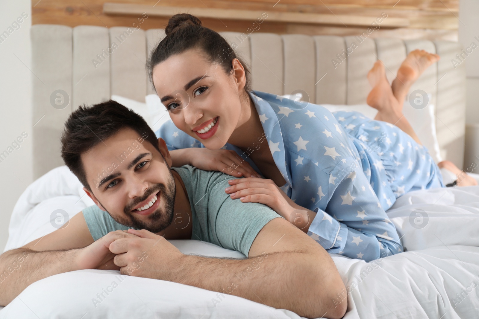 Photo of Happy couple in pajamas on bed at home