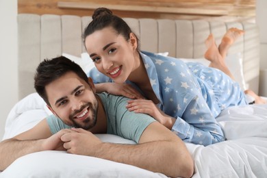 Happy couple in pajamas on bed at home