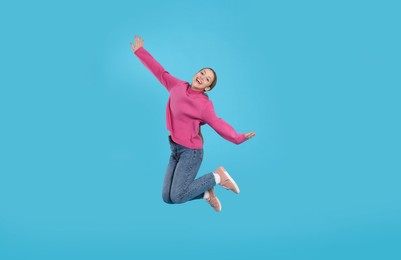 Photo of Teenage girl in casual clothes jumping on light blue background