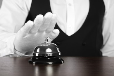 Photo of Butler ringing service bell at table, closeup