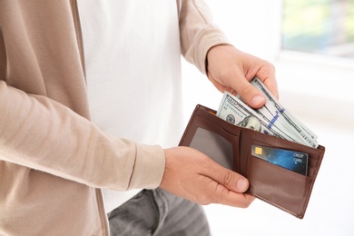 Photo of Man holding wallet with money on blurred background, closeup