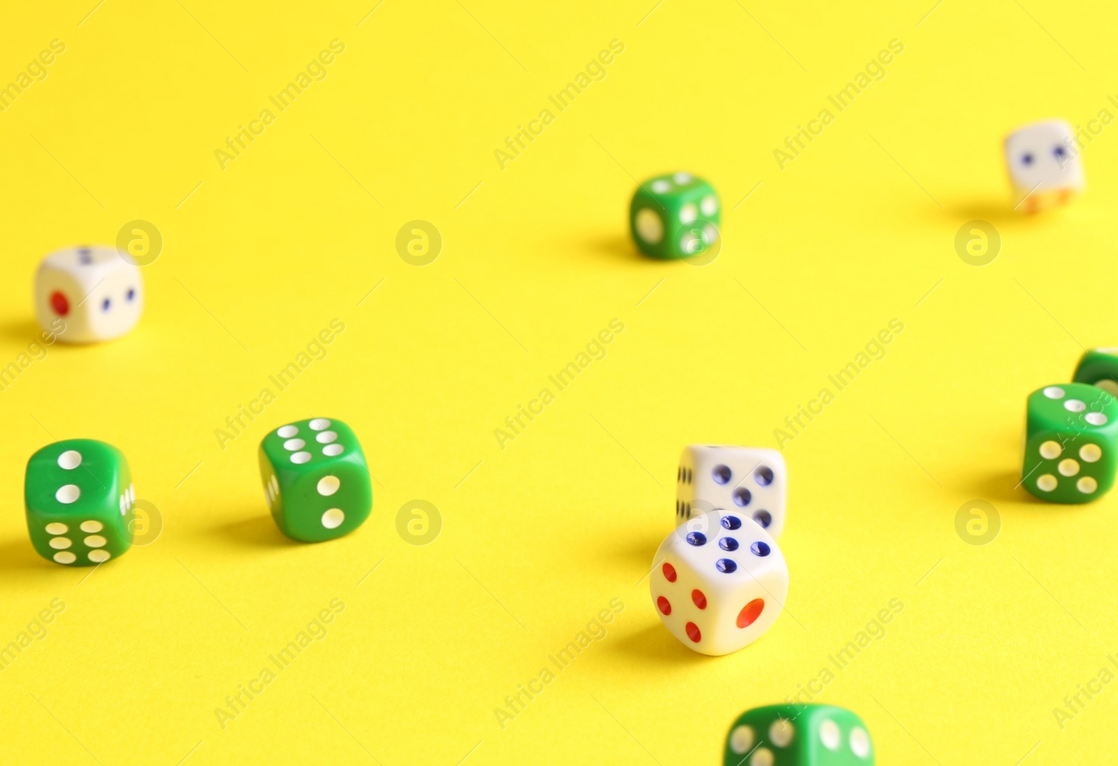 Photo of Many color game dices falling on yellow background