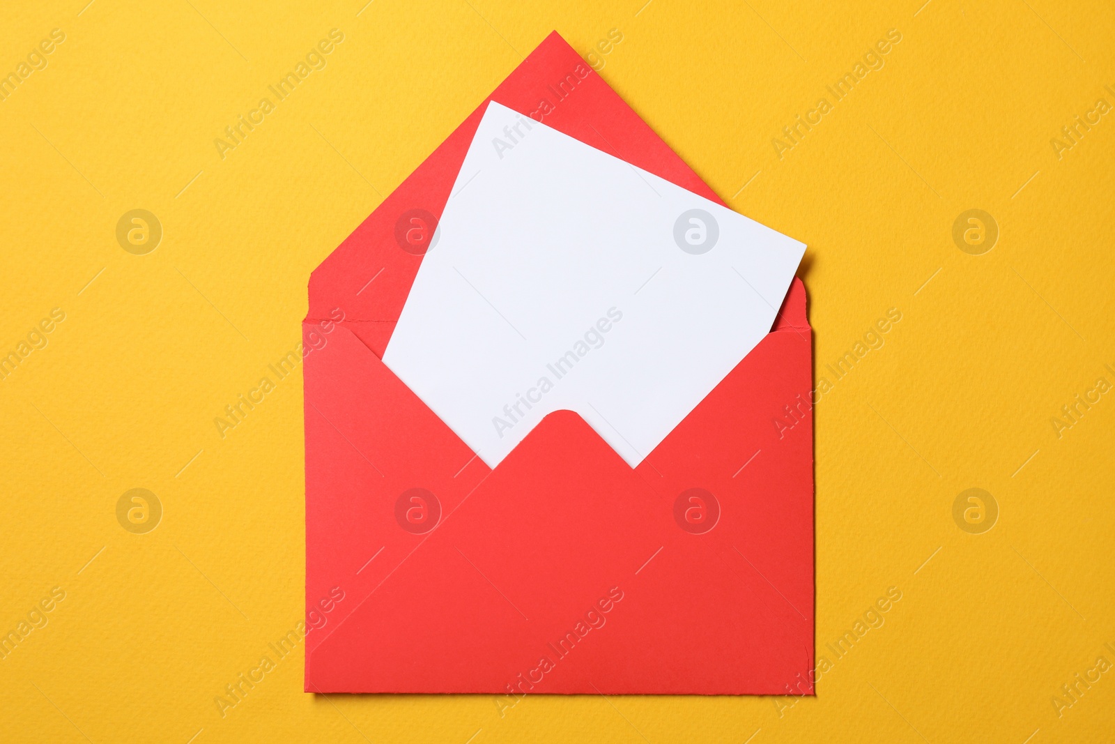 Photo of Blank sheet of paper in open letter envelope on orange background, top view