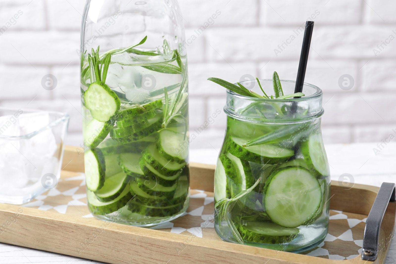 Photo of Natural lemonade with cucumber and rosemary in glassware on table