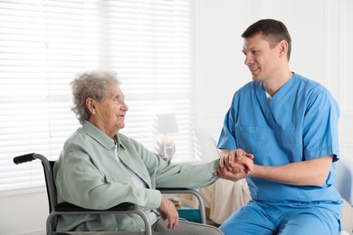 Photo of Caregiver examining senior woman in room. Home health care service