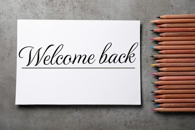 Image of Paper with phrase Welcome Back and pencils on grey table, flat lay