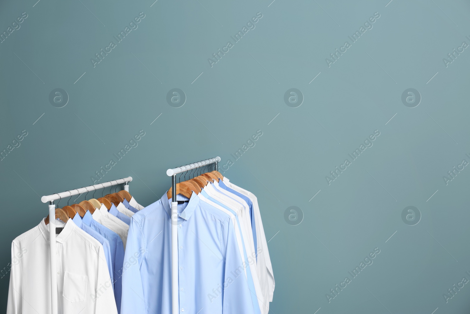 Photo of Racks with clean clothes after dry-cleaning against color background